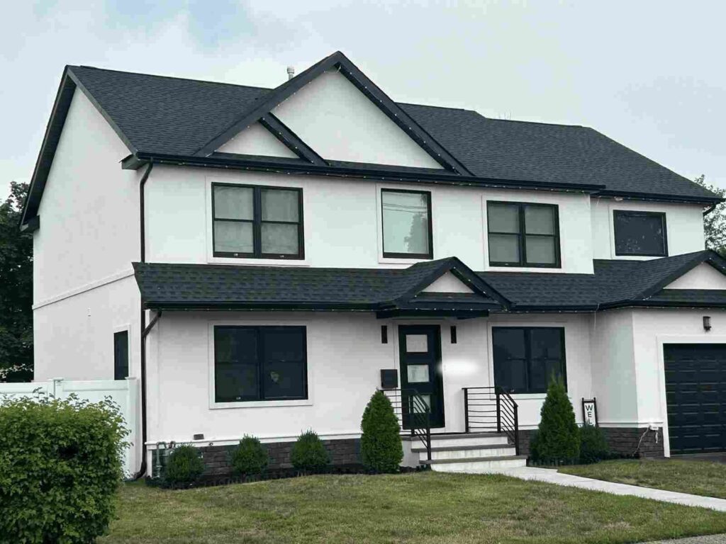 Two-story house with white and dark trim exterior, steeply pitched roof, and attached garage.