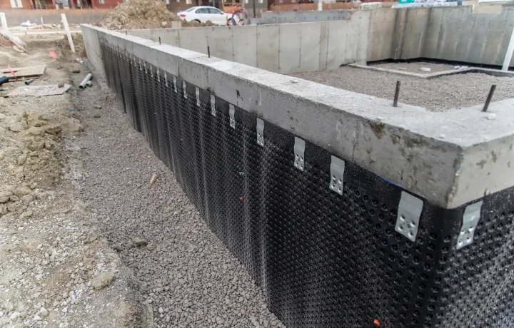 Close-up view of foundation wall with black waterproofing membrane