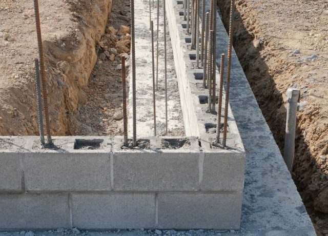 Initial stages of CMU block wall construction with rebar in a trench