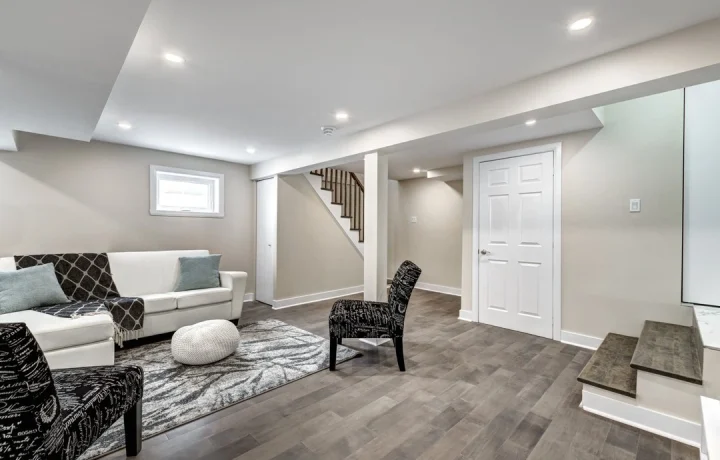 Finished basement with modern seating area, exposed beams, and recessed lighting.