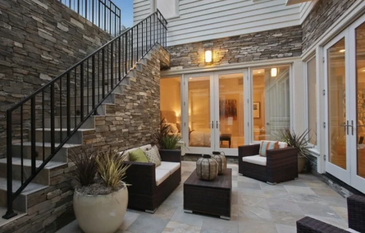 Side entrance to basement with black metal stairs and railing, leading to a white door