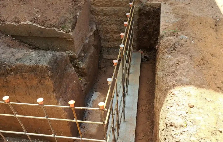 Excavated area with wooden formwork and metal rebar grid structure for home foundation construction