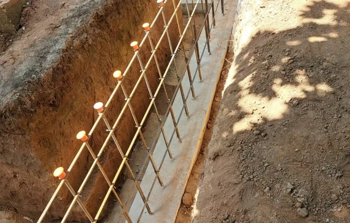 Close-up view of concrete footings by metal rebar grid structure in an excavation for home foundation construction