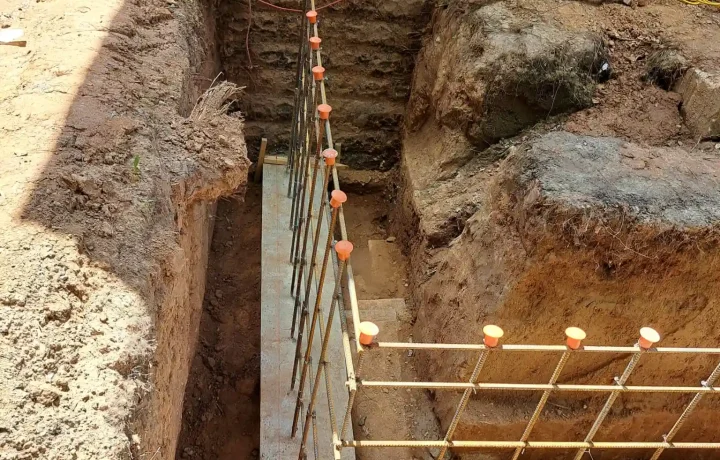 Excavated area with wooden formwork and metal rebar grid structure for home foundation construction