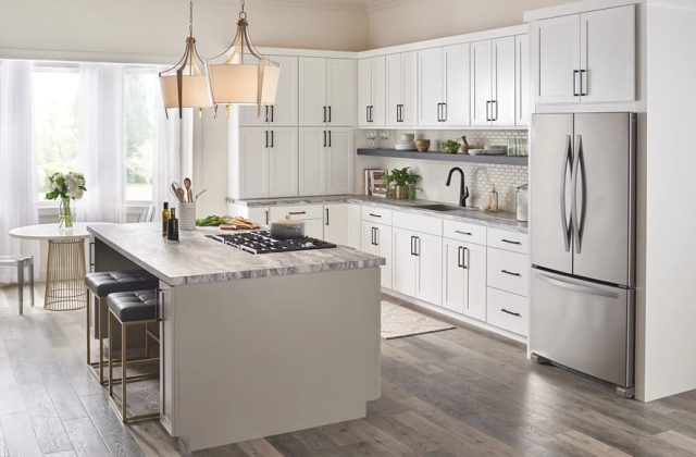 Modern kitchen interior with white cabinetry, stainless steel appliances, and a marble countertop island.