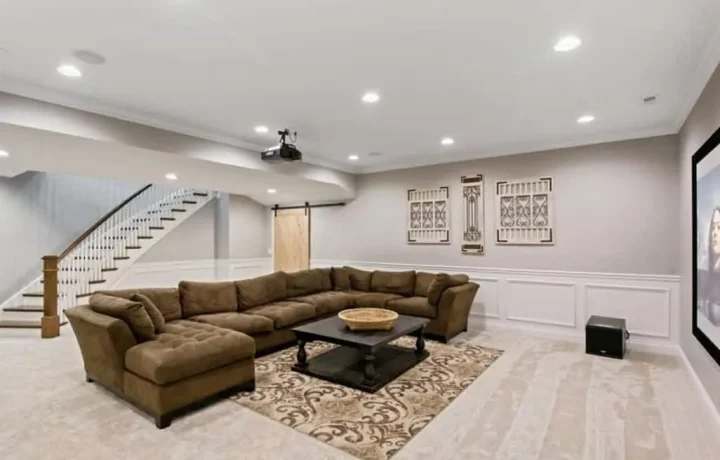 Finished basement with L-shaped brown sofa, wall-mounted flat-screen TV, and recessed lighting in Ontario