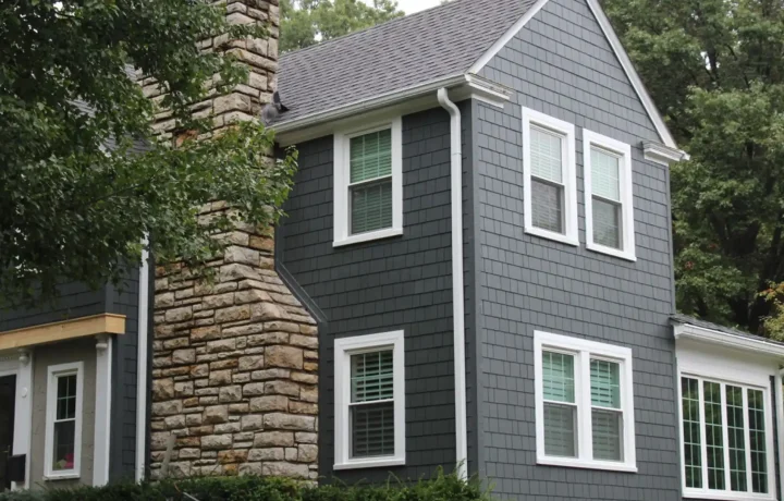 Two-story house with gray siding, white trim, and a prominent stone chimney