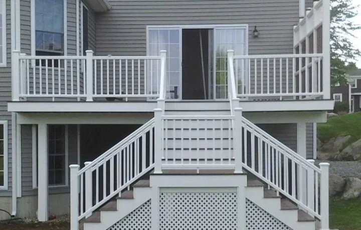 Elevated porch with white railings and symmetrical wooden stairs, featuring lattice work underneath