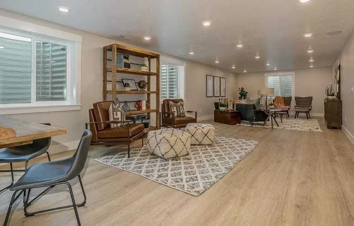 Finished basement with seating area, wooden shelf unit, and recessed lighting