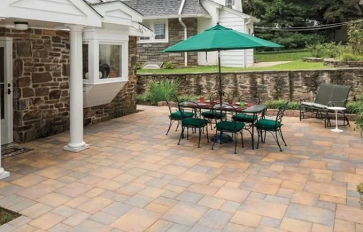 Outdoor patio with stone floor, green dining set under umbrella, and reclining sun chair