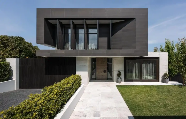 Modern two-story house with cantilevered upper level, large glass windows, and landscaped garden- house addition contractors