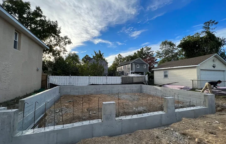 Construction site with steel rebar laid out within concrete foundation walls